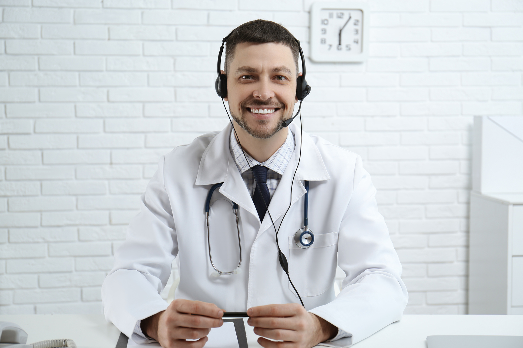 Doctor with Headset Sitting at Desk in Clinic. Health Service Hotline